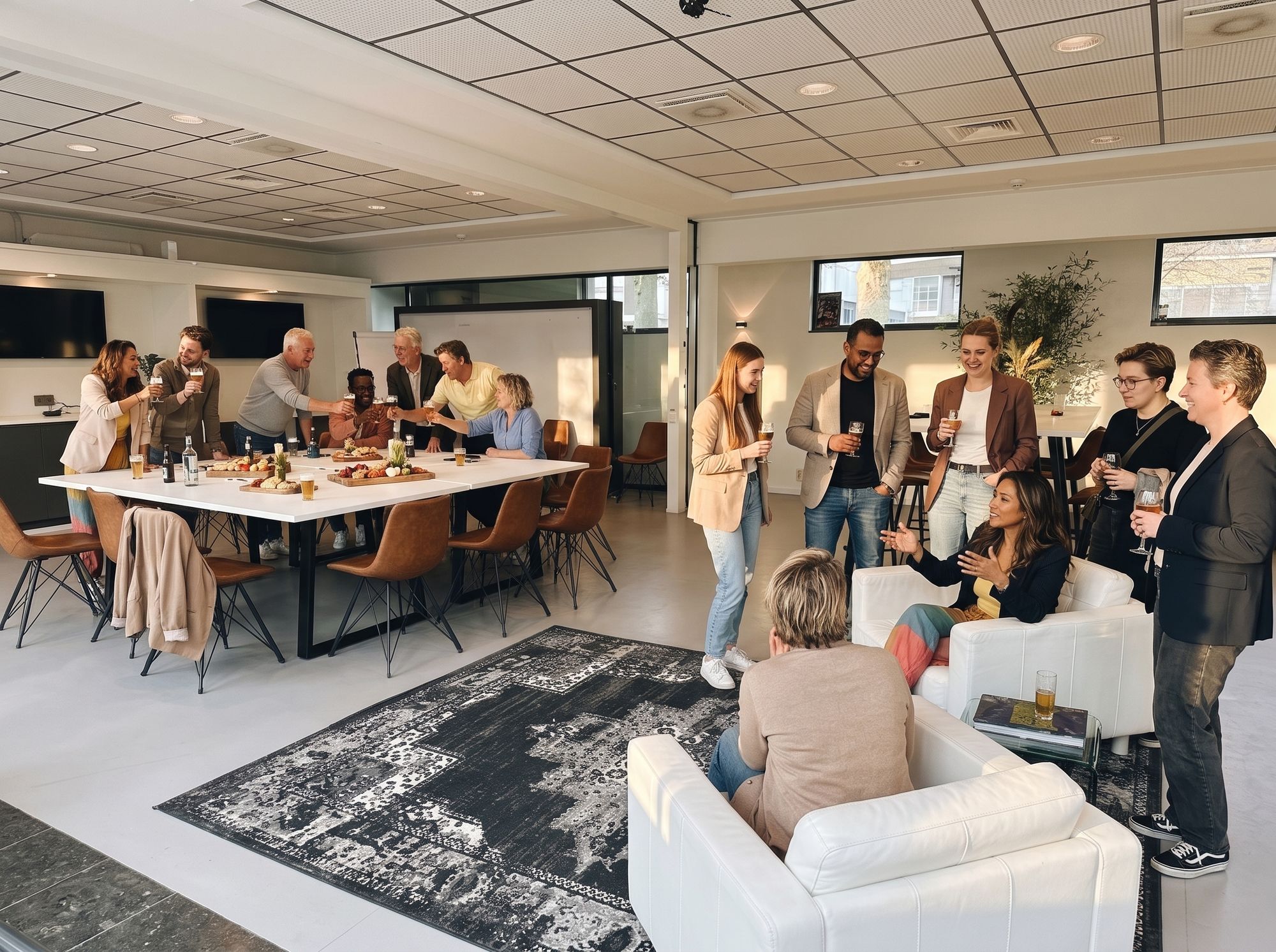 Collega's borrelen met een drankje in de zaal van Third Place, bij de grote witte tafel met hapjes en in de witte fauteuils