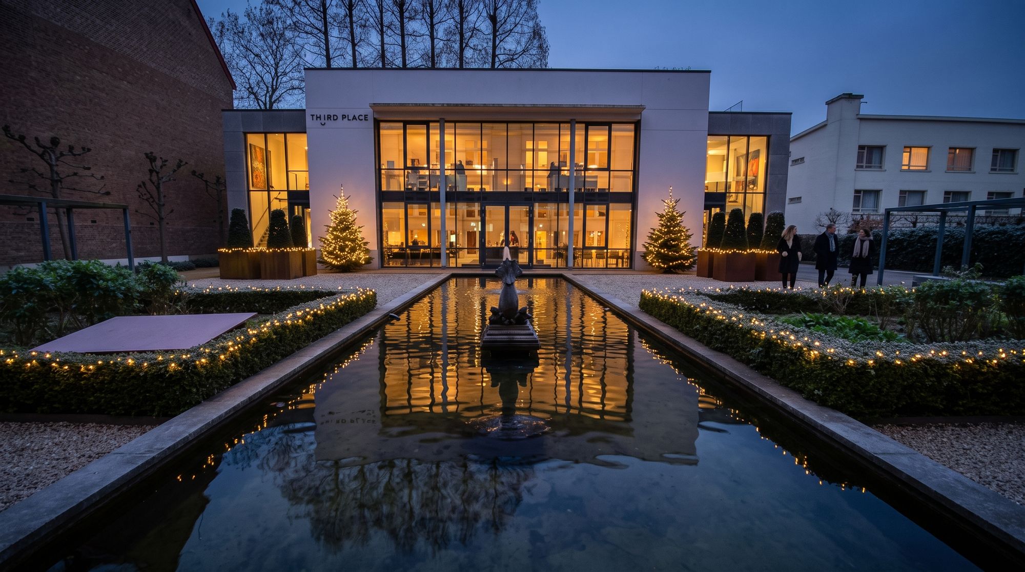 Third Place in de decemberschemer: het witte huis met glazen voorgevel, de lange waterpartij en de haag met lichtjes in de tuin